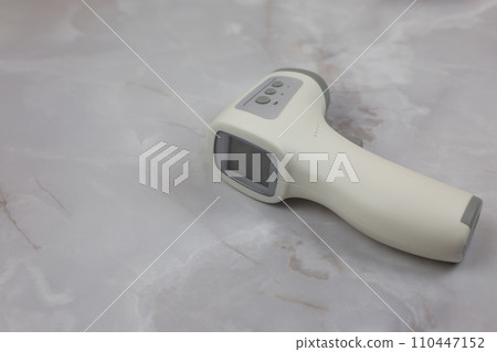 Scanner for measuring temperature without contact with the screen lies on the white table, modern thermometer Scanner for measuring temperature without contact with the screen lies on the white table, modern thermometer 110447152