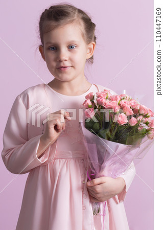 A cute little girl in a pink dress holds a bouquet of pink roses A cute little girl in a pink dress holds a bouquet of pink roses 110447169
