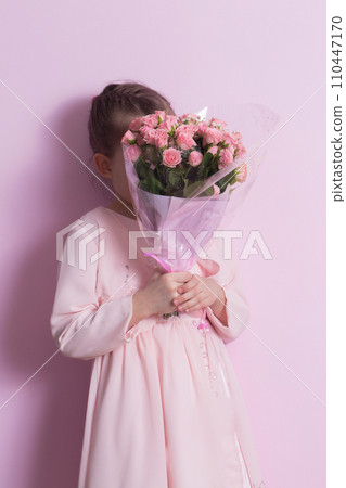 A cute little girl in a pink dress holds a bouquet of pink roses A cute little girl in a pink dress holds a bouquet of pink roses 110447170