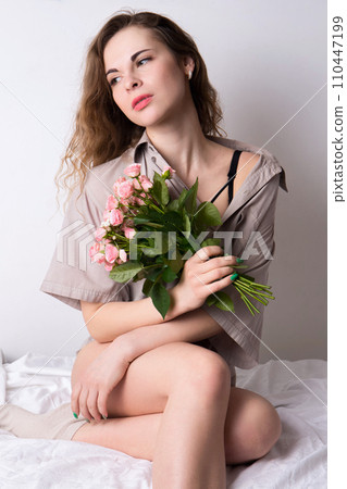 young woman in a shirt with a bouquet of roses 110447199