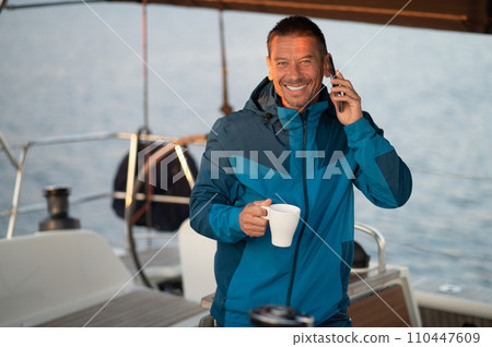 Man on the yacht with a cup of coffee talking on the phone 110447609