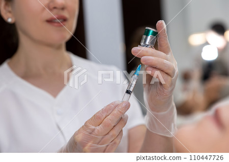 Beautician preparing beauty injections for female patient 110447726