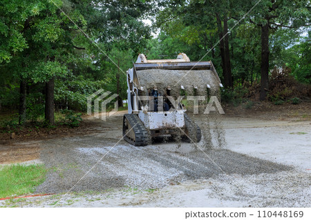 As construction works with bobcat mini loader, crushed stone gravel is being moved using buckets As construction works with bobcat mini loader, crushed stone gravel is being moved using buckets 110448169