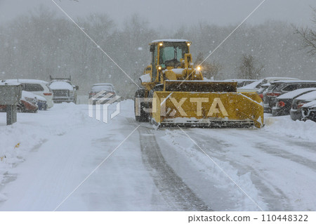 Tractor removes snow from road following snowfall in winter time Tractor removes snow from road following snowfall in winter time 110448322