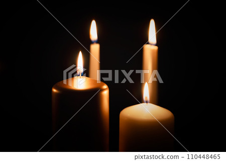 Candles burning in darkness over black background Candles burning in darkness over black background 110448465