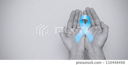 Hand holding blue prostate cancer awareness ribbon 110448498