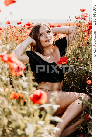 Woman poppies field. portrait happy woman with long hair in a poppy field and enjoying the beauty of nature in a warm summer day. 110448976