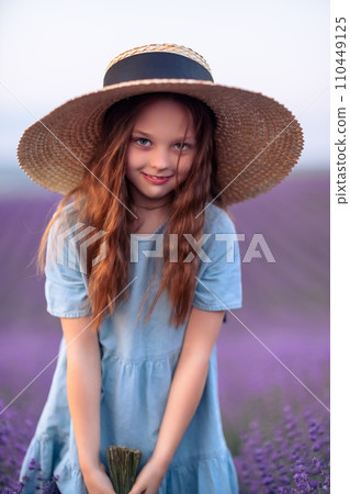 Girl lavender field. Laughing girl in a blue dress with flowing hair in a hat stands in a lilac lavender field Girl lavender field. Laughing girl in a blue dress with flowing hair in a hat stands in a lilac lavender field 110449125