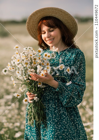 Happy woman in a field of daisies with a wreath of wildflowers on her head. woman in a green dress in a field of white flowers. Charming woman with a bouquet of daisies, tender summer photo Happy woman in a field of daisies with a wreath of wildflowers on her head. woman in a green dress in a field of white flowers. Charming woman with a bouquet of daisies, tender summer photo 110449672