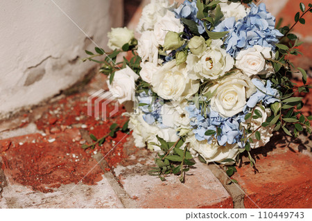 Festive wedding bouquet tied with a ribbon on a brick background. Festive wedding bouquet tied with a ribbon on a brick background. 110449743