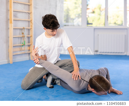 Teenage boy and middle-aged man training arm twist technique during self-defense courses Teenage boy and middle-aged man training arm twist technique during self-defense courses 110450883