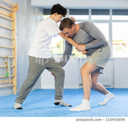 Teenage boy and middle-aged man training throwing method during self-defense courses 110450894