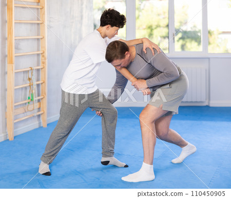 Father teaching his son wrestling or self-defense techniques in gym 110450905