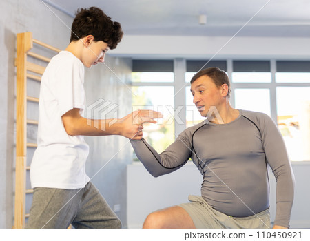 Teenage boy and middle-aged man training arm twist technique during self-defense courses 110450921
