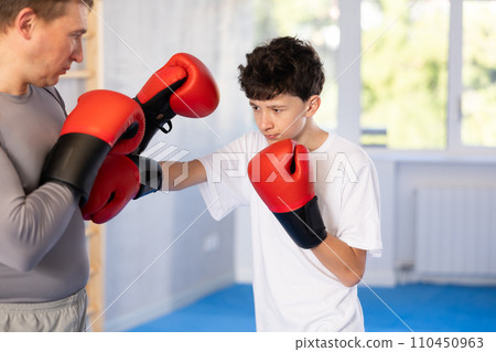 Middle-aged man and teenage boy training boxing during sports classes Middle-aged man and teenage boy training boxing during sports classes 110450963