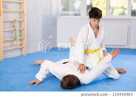 Teenage boy applying judo techniques on middle-aged trainer during sports classes Teenage boy applying judo techniques on middle-aged trainer during sports classes 110450965