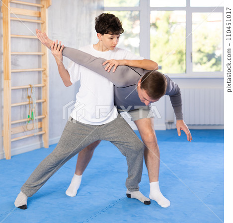 Man and boy teenager training self-defense techniques 110451017