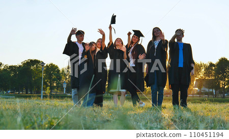 Student alumni waving at sunset. 110451194