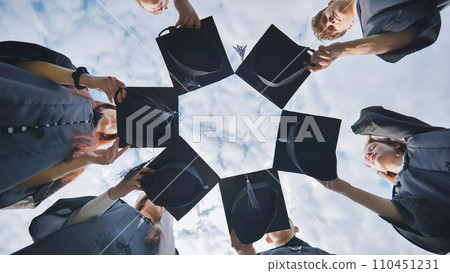 Graduates in black robes join their caps in a circle. Graduates in black robes join their caps in a circle. 110451231