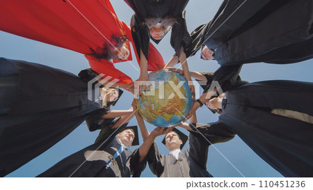 College graduates stand in a circle and hold a geographical globe of the world. College graduates stand in a circle and hold a geographical globe of the world. 110451236