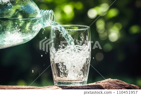 Drink water pouring in to glass mug from water plastic bottle on green background. Drink water pouring in to glass mug from water plastic bottle on green background. 110451957