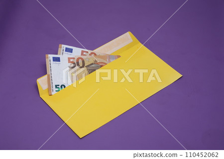 Banknotes in a yellow envelope on a purple background. Bribery concept. Salary in envelopes. Financial fraud. 110452062