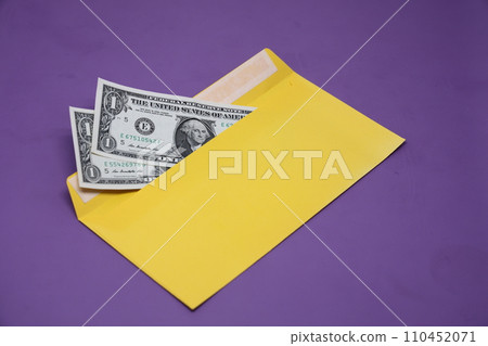 Banknotes in a yellow envelope on a purple background. Bribery concept. Salary in envelopes. Financial fraud. Banknotes in a yellow envelope on a purple background. Bribery concept. Salary in envelopes. Financial fraud. 110452071
