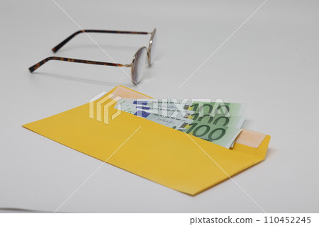 banknotes in a yellow envelope. open envelope with banknotes on a light background. banknotes in a yellow envelope. open envelope with banknotes on a light background. 110452245