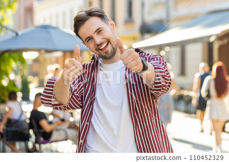 Happy man showing thumbs up, like sign positive something good positive feedback in city street 110452329