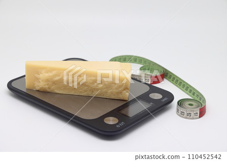 a piece of cheese and a tailor meter isolated on a light background, proper nutrition, counting calories. 110452542
