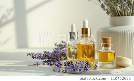 Beauty product display, slender flacons and oils, arranged with fresh lavender, on a monochrome ivory surface 110452633