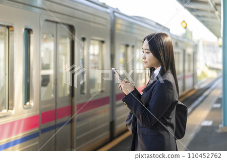 High school girl with a smartphone waiting for the train on the station platform 110452762