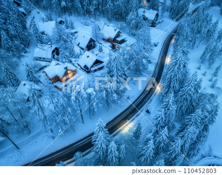 Aerial view of snowy village, road, trees, houses at night 110452803