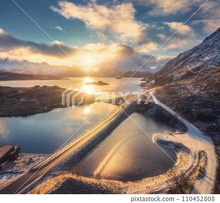 Aerial view of bridge, sea and snowy mountains at sunrise Aerial view of bridge, sea and snowy mountains at sunrise 110452808