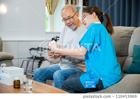 Asian doctor with physician visit senior male patient consult medicine dosage at house in living room, Woman nurse caregiver showing prescription drug to senior man at nursing home, healthcare support 110453069