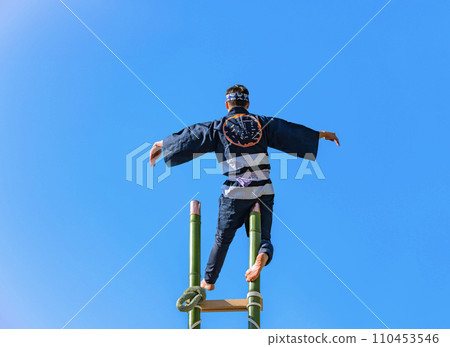 [Yotsuya, Tokyo] A firefighter stands in the air at the top of a high bamboo ladder and performs acrobatics. 110453546