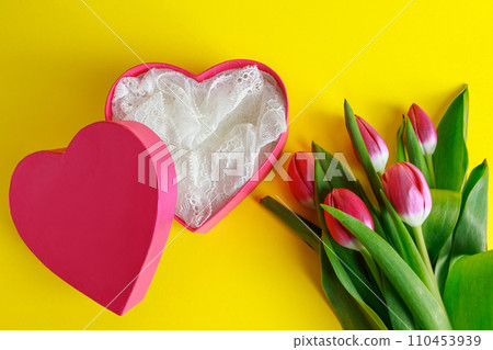 Pink heart and tulips on yellow background. Valentine's day concept, place for text. Pink heart and tulips on yellow background. Valentine's day concept, place for text. 110453939