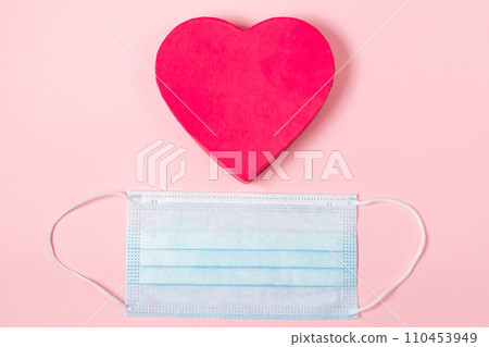 Valentine's day concept during the coronavirus pandemic. Pink heart and medical mask. Place for text. Valentine's day concept during the coronavirus pandemic. Pink heart and medical mask. Place for text. 110453949