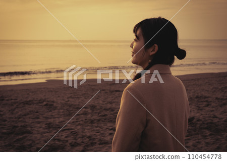 Young woman enjoying the sunset at the sea in winter 110454778