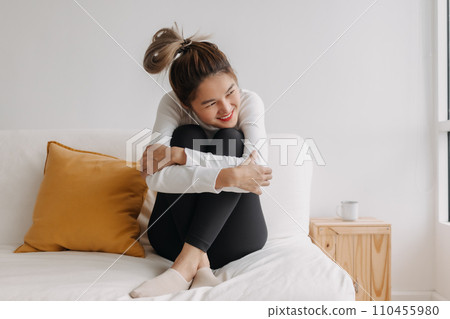Happy asian woman hug herself on sofa for warmth in good chill winter morning 110455980
