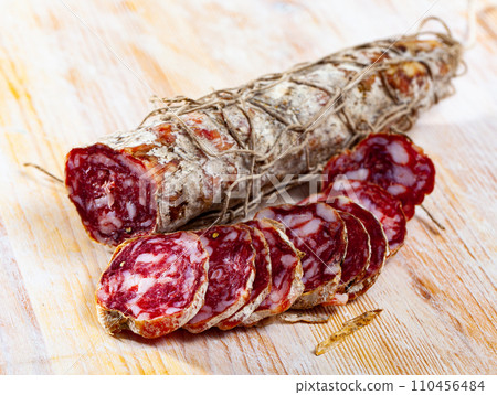Piacenza salami cut in slices on a wooden surface, close-up 110456484