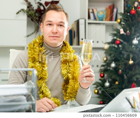 Happy man sitting at desk in office with glass of champagne 110456609