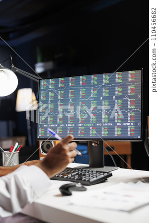 This image shows a pc monitor displaying financial reports while a businessman writes down notes. Detailed view of the computer screen having research and statistics information. This image shows a pc monitor displaying financial reports while a businessman writes down notes. Detailed view of the computer screen having research and statistics information. 110456682