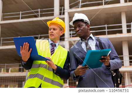 Architect and foreman must write documents and drawings on laptop with building construction 110456731