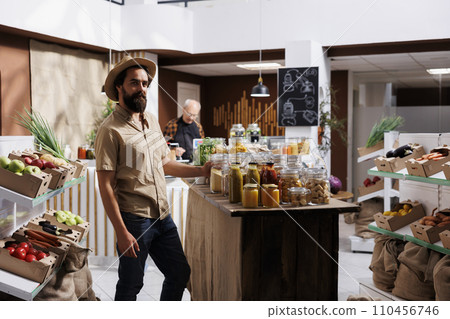 Portrait of cheerful man looking for farm grown vegetables in sustainable zero waste store. Hipster client does grocery shopping, buying chemicals free food in local neighborhood store 110456746
