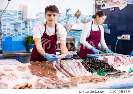 Positive salesman demonstrating lucet fish in fish store Positive salesman demonstrating lucet fish in fish store 110456879