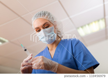 Female doctor in mask preparing syringe for vaccination Female doctor in mask preparing syringe for vaccination 110456979