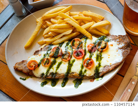Beef steak with mozzarella, tomatoes and pesto served with fries Beef steak with mozzarella, tomatoes and pesto served with fries 110457114
