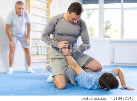 Two athlete men of different age in sportswear practicing self-defense sparring in hall Two athlete men of different age in sportswear practicing self-defense sparring in hall 110457145