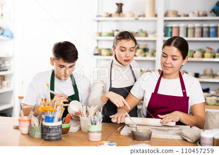 Two young women and young man making pottery Two young women and young man making pottery 110457259